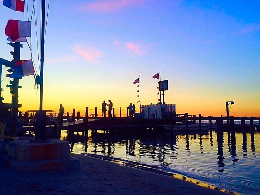 Sunset over the bay from the docks in Point Lookout, NY, with signal flags and a pier in silhouette
