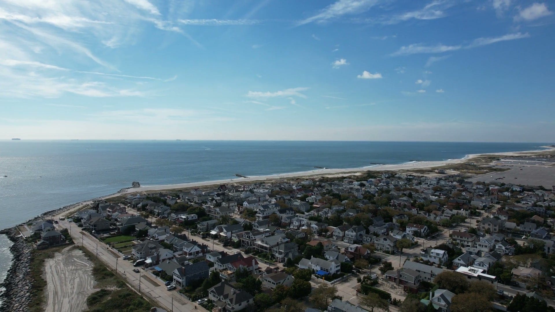 Point Lookout from the air: houses, the ocean beach and the rock-lined shore at the inlet end